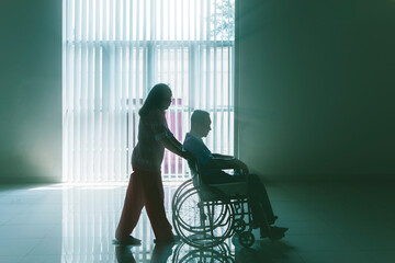 Silhouette of old woman push husband on wheelchair - Powered by Adobe
