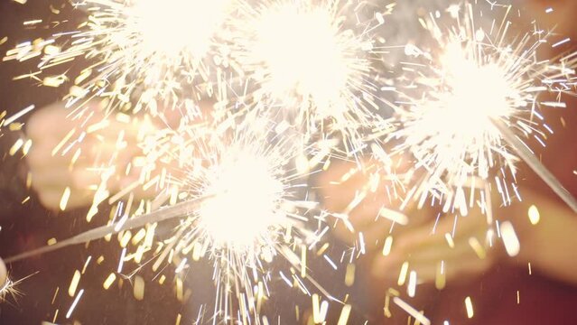 Asian girl and group young college student friends lit light sparkler in hand fireworks, sing and dance together. Woman on Party with people, love friendship relationship and celebration concept.