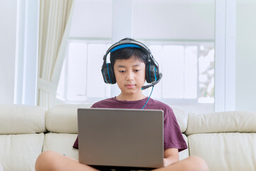 Bored preteen boy using a laptop at home