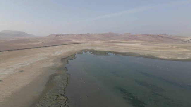 Aerial flyover: Empty desert landscape around muddy salt lagoon