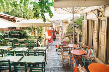 Athens, Greece, beautiful street in old district of Plaka. Colorful view of greek street with cafe tables and flowers. Famous tourist destination and travel attraction in Europe.