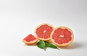 Cut grapefruit on a white background, decorated with leaves and a slice of grapefruit