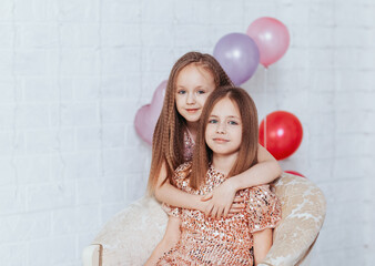 Beautiful little sisters girls joking at birthday party. young ladies with balloons preparing for...