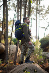 Determined male hiker in forest. Man with backpack with casual clothes standing on hill. Nature, leisure, hobby concept