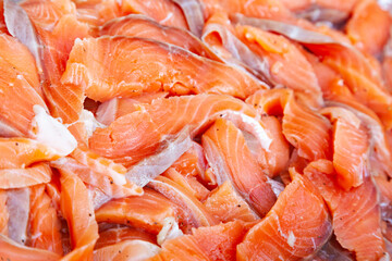 Pieces of salmon fillet. Many pieces of salted, finely chopped red fish close-up.