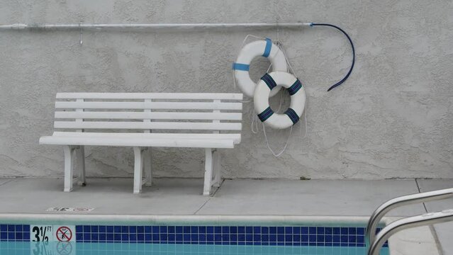 Round rescue lifebuoy for safety on water in swimming pool by motel, California, USA. Blue lifeguard ring buoy and bench for drowning precaution on summer vacations in hotel. Emergency lifesaver.