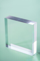 Acrylic Solid Display Block for Shop Windows on green background, empty podium for product presentation, geometric stand for cosmetics