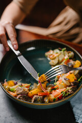 girl eating salad with stewed veal cheeks, potato wedges, tomatoes and mustard sauce