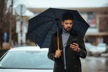 Afro male using cellphone under umbrella