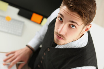 Man look up, make notes on paper, employee in suit at working place