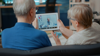 Senior couple attending online meeting with doctor on digital tablet, doing remote consultation at...