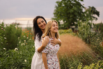 Happy mother's day. A young mother with a teenage daughter spends time in the garden. Mom and her daughter teenage girl are playing, smiling and hugging. Loving single mother hugs cute daughter.