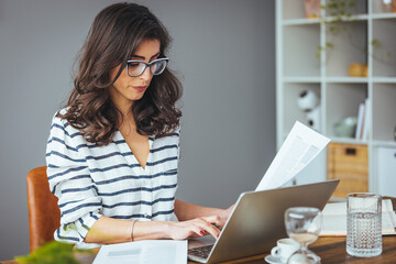 A business woman does banking and administrative work by keeping accounts at home. She counts...