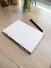 checkered notepad and black pen on wooden table