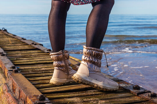 woman walks around an old mole at sea