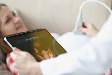 Doctor conducting ultrasound examination of patients belly in clinic, qualified medical worker