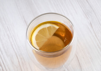 Tea with lemon in a glass cup on a wooden table, free space, close-up. Useful drink. Warming drink