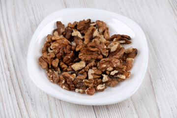 Walnuts on a white plate, side view. Walnut kernels on the table. Healthy food