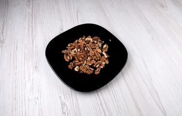 Walnuts on a black plate, on a wooden table. Healthy food