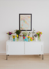 White sideboard with flower bouquet vases and decorative map