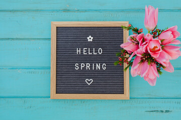 Welcome spring retro sign on turquoise wood background with plants and flowers