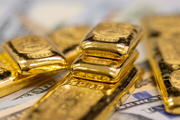 pile of pure gold bars, bullion, ingot on background of US dollar banknotes