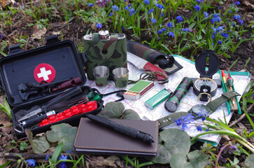 A set of items for survival in nature laid out in a clearing in the forest.