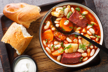 Babgulyas is gulyas soup with beans, meat, celery, carrot and onion closeup in the plate on the wooden tray. Horizontal top view from above