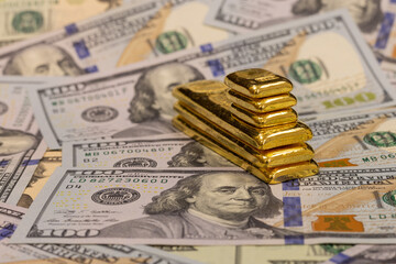 pile of long and short pure gold bars, bullion, ingot on background of US dollar banknotes