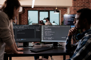 Multiethnic cyber security team members in agency office writing cloud database processing algorithm. Software developers sitting at desk and developing a functional data encryption system.
