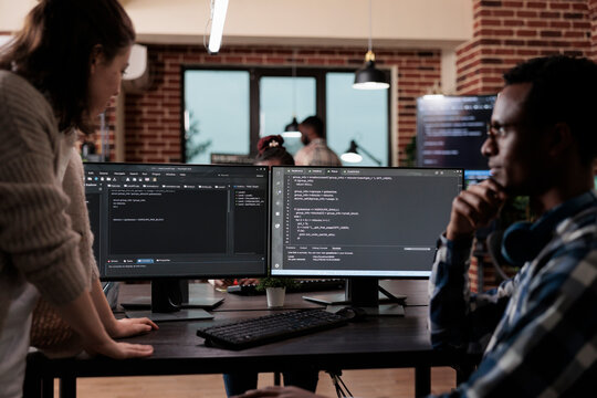 Multiethnic cyber security team members in agency office writing cloud database processing algorithm. Software developers sitting at desk and developing a functional data encryption system.