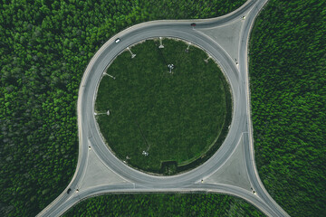 Aerial view of a traffic roundabout and road junctions in green forest