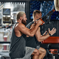 A man trains his arms and chest in the gym on the simulator, does exercises for different muscle groups. Fintes motivation, sports lifestyle, health, athletic body, body positive. Film grain.