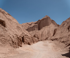 Fototapeta premium Hiking through the narrow desert trails of the Quebrada de Chulakao (aka., Devil’s Throat). Dramatic sand, dunes and rock formations. San Pedro de Atacama, Cordillera de la Sal. Chile
