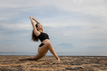 Stretching exercise in the morning. Sportive and athletic young female warming up on the beach. Fitness, sport, wellness concept. Healthy lifestyle. Active Caucasian woman workout. Bali