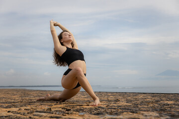 Stretching exercise in the morning. Sportive and athletic young female warming up on the beach. Fitness, sport, wellness concept. Healthy lifestyle. Active Caucasian woman workout. Bali