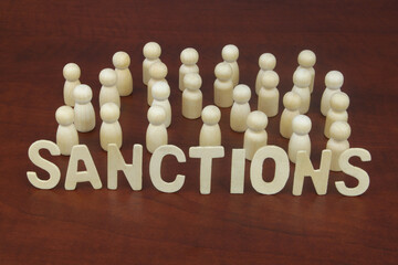 People and sanctions concept. Many wooden people figures and letters sanctions.