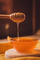 Honey dripping from honey dipper in bowl. Close-up. Healthy organic Thick honey dipping from the...