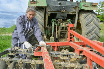 Couple of farmers working with tractor in agricultural field