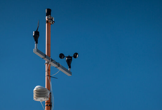 A small meteo station on top of a house against blue sky background. Meteorology as a hobby.