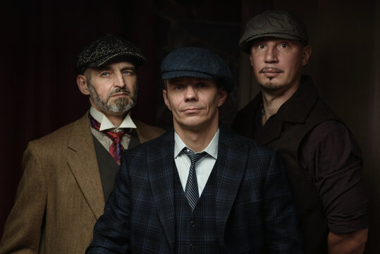 Three men of different ages, an English retro gangster of the 1920s, dressed in a coat, suit and flat cap