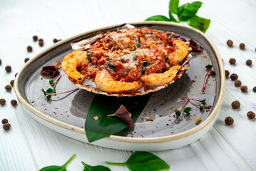 Shrimps baked in scallop shell with tomato sauce and vegetables