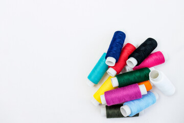 Multicolored threads for sewing on a white cotton fabric background.selective focus