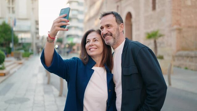 Man and woman couple hugging each other make selfie by the smartphone at street