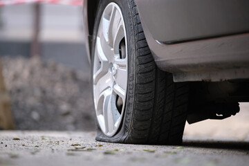 Car with punctured flat tire parked on roadside