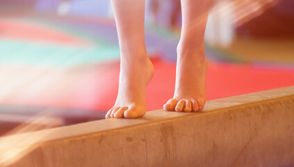 Young female barefoot on balance beam gymnastic balance practicing background