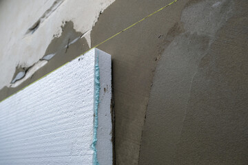 Installation of styrofoam insulation sheets on house facade wall for thermal protection