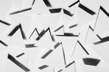 White triangles geometric pattern in hard light with strict black shadows in random with sharp angles, top view. Energy and aggressive modern abstract background in minimal style.