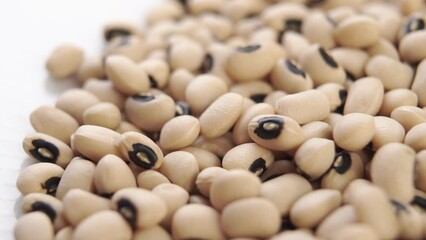 Kidney black eyed beans falling in slow motion on a white dish. Dry uncooked legumes. Macro. Rotation