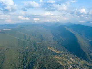Green slopes of Ukrainian Carpathian mountains in summer. Cloudy day, low clouds. Aerial drone view.